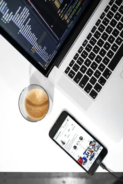 Ordinateur, café et smartphone posés sur un bureau.