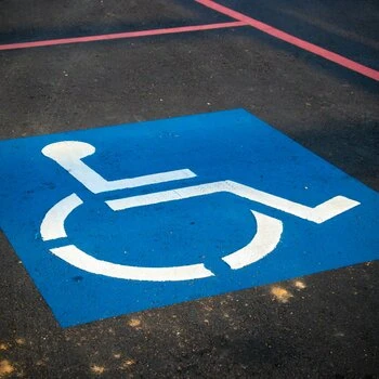 Peinture d'un symbole de fauteuil roulant pour handicapés sur du bitume.